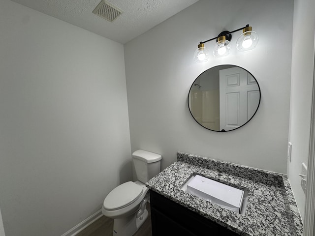 bathroom with baseboards, visible vents, toilet, a textured ceiling, and vanity