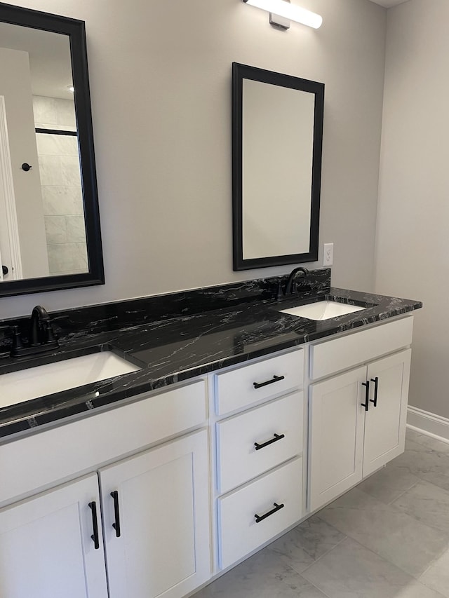 full bathroom with marble finish floor, double vanity, and a sink