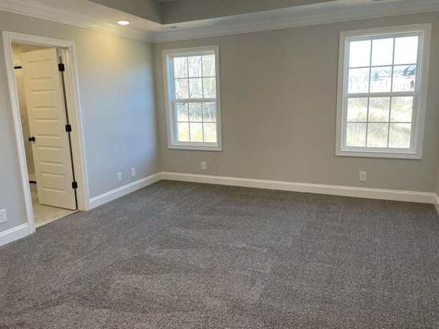 spare room featuring baseboards, ornamental molding, and dark colored carpet