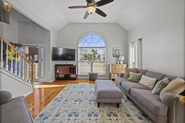 living area featuring lofted ceiling, ceiling fan, stairway, and wood finished floors