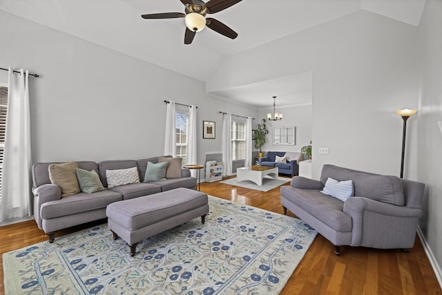 living area with baseboards, vaulted ceiling, wood finished floors, and ceiling fan with notable chandelier