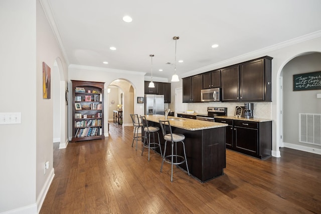 kitchen with arched walkways, a sink, visible vents, a kitchen breakfast bar, and appliances with stainless steel finishes