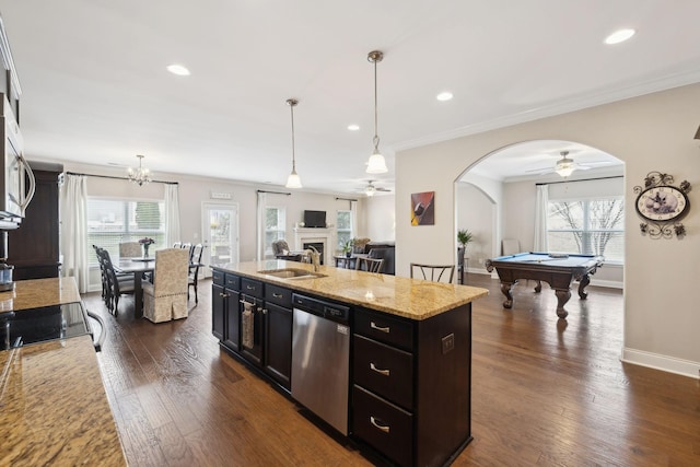 kitchen with arched walkways, dark wood finished floors, dishwasher, a fireplace, and a sink