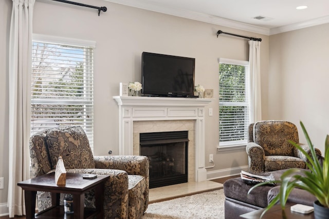 living area with baseboards, visible vents, a premium fireplace, wood finished floors, and crown molding