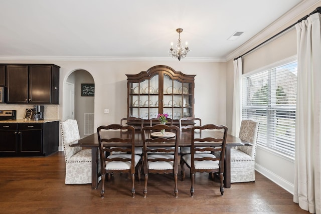 dining area with dark wood-style floors, visible vents, arched walkways, and crown molding