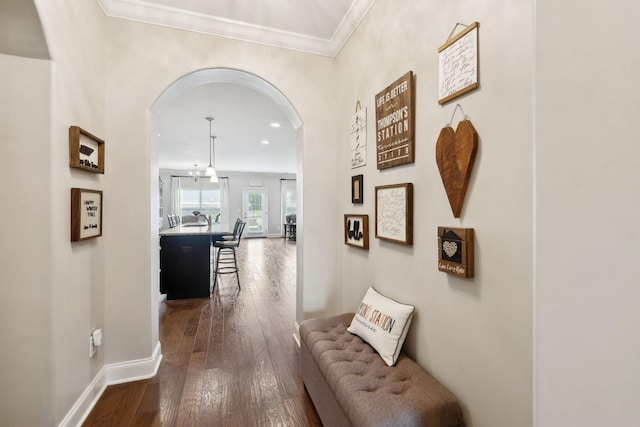 hall featuring crown molding, dark wood-style flooring, arched walkways, and baseboards