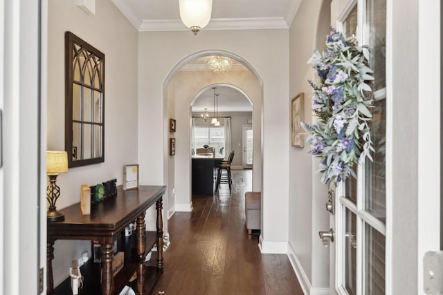 entryway with dark wood-style floors, arched walkways, crown molding, an inviting chandelier, and baseboards