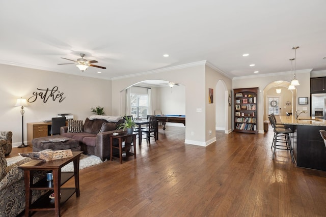 living room with baseboards, arched walkways, dark wood finished floors, and a ceiling fan