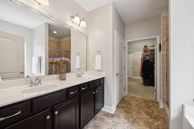 full bathroom featuring double vanity, a sink, a shower stall, and a spacious closet