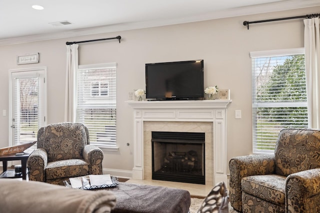 living room with a healthy amount of sunlight, visible vents, crown molding, and a high end fireplace