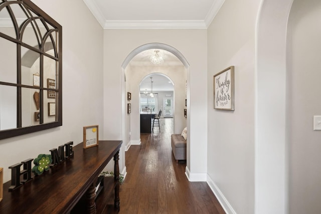 corridor with dark wood-style floors, arched walkways, a notable chandelier, crown molding, and baseboards