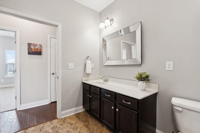 bathroom with toilet, vanity, and baseboards