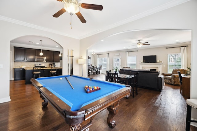 game room with dark wood-style floors, a fireplace, and crown molding