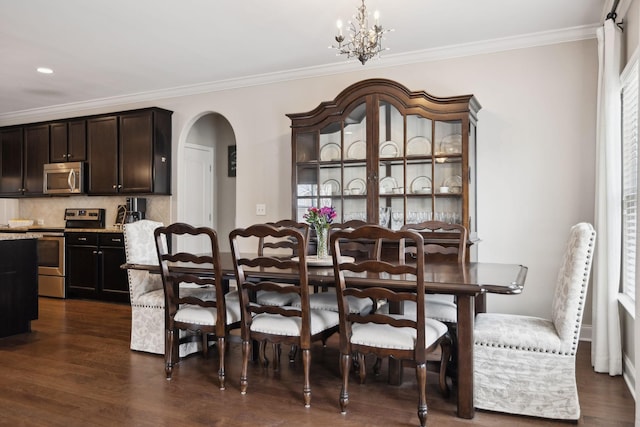 dining space featuring crown molding, arched walkways, dark wood finished floors, and an inviting chandelier