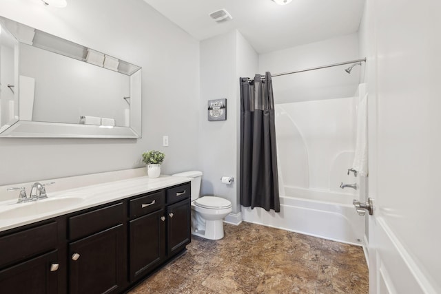 full bathroom with stone finish flooring, shower / tub combo with curtain, vanity, and toilet