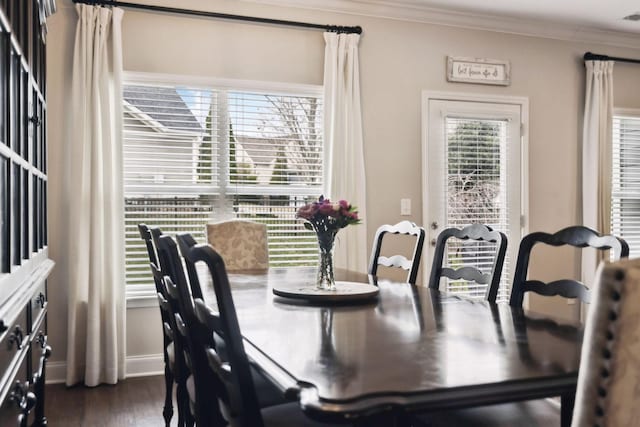 dining space featuring dark wood finished floors, crown molding, and baseboards