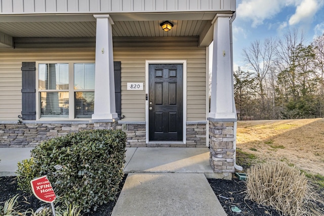 doorway to property with covered porch and stone siding