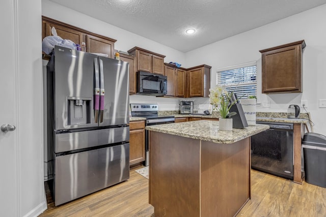 820 Lower Park Pl, Antioch, TN 37013 - kitchen with black appliances, a kitchen island, light wood-style flooring, and light stone countertops