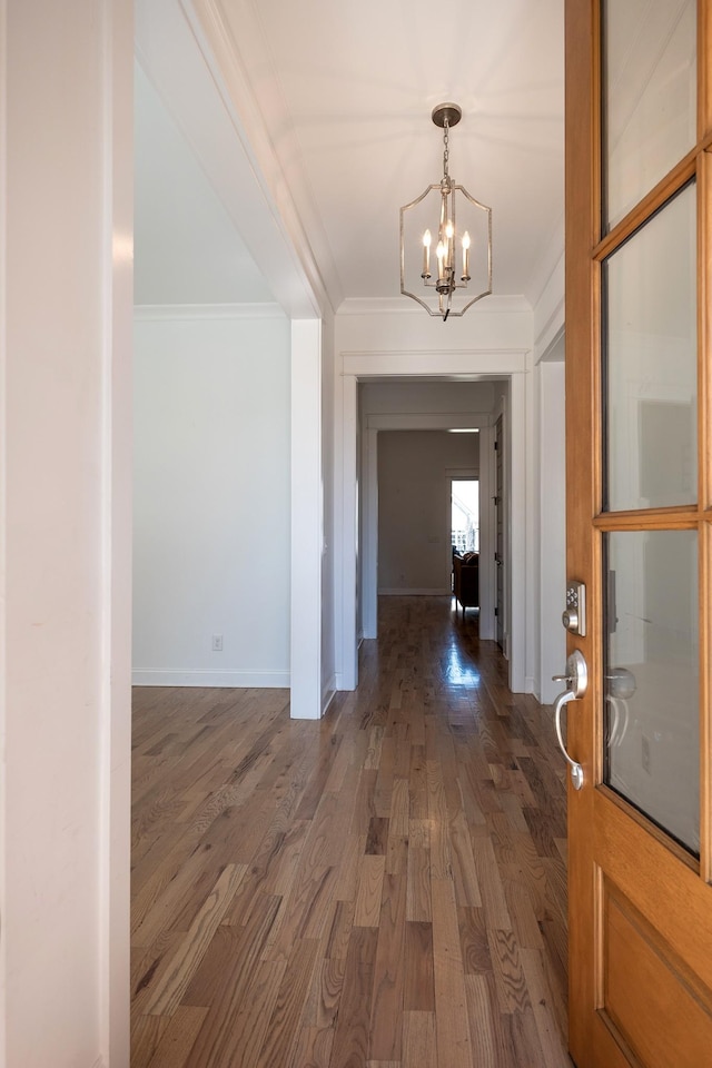 interior space featuring ornamental molding, baseboards, an inviting chandelier, and wood finished floors