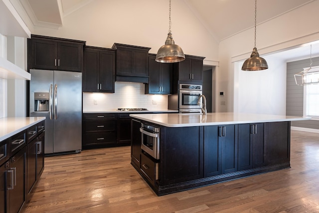 kitchen with appliances with stainless steel finishes, tasteful backsplash, light countertops, and wood finished floors