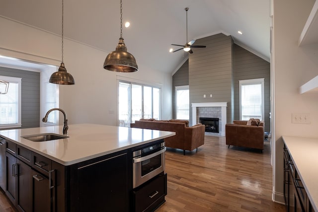 kitchen with stainless steel oven, light countertops, a sink, and wood finished floors