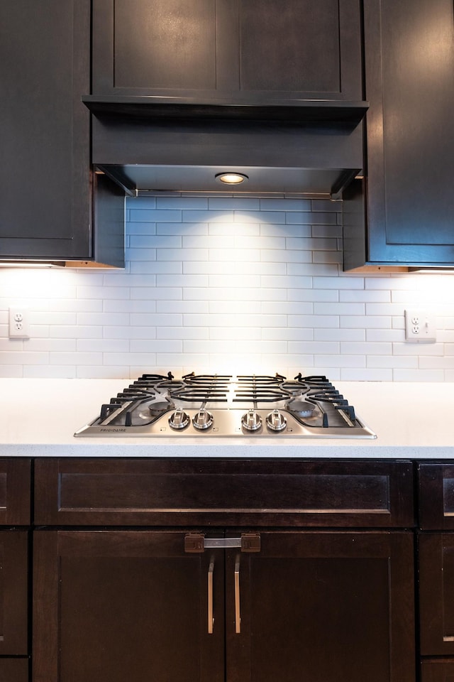 kitchen with range hood, light countertops, stainless steel gas cooktop, and dark brown cabinetry