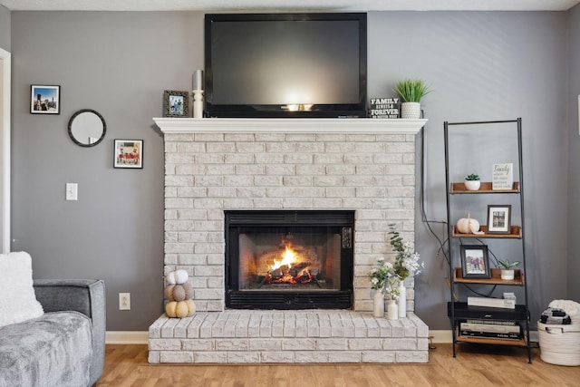 interior space featuring a brick fireplace, baseboards, and wood finished floors