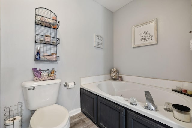 full bathroom featuring baseboards, a whirlpool tub, toilet, and wood finished floors