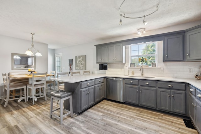 kitchen with dishwasher, a peninsula, a sink, and gray cabinetry