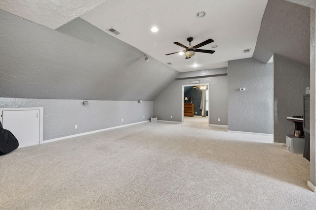 additional living space featuring vaulted ceiling, a textured wall, visible vents, and baseboards