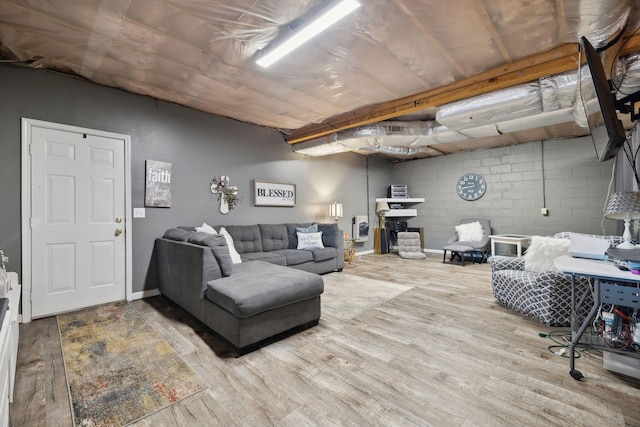 living area featuring concrete block wall, heating unit, and wood finished floors