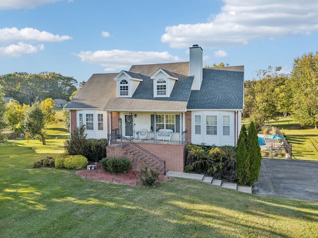 cape cod-style house with covered porch, brick siding, a front lawn, and stairs