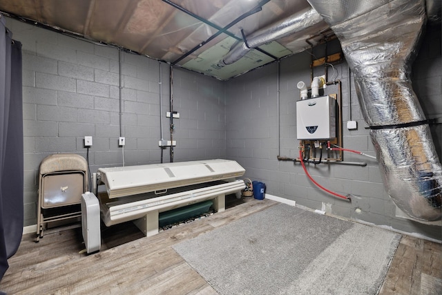 misc room featuring water heater, wood finished floors, and concrete block wall