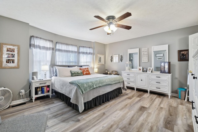 bedroom featuring a textured ceiling, light wood finished floors, and baseboards