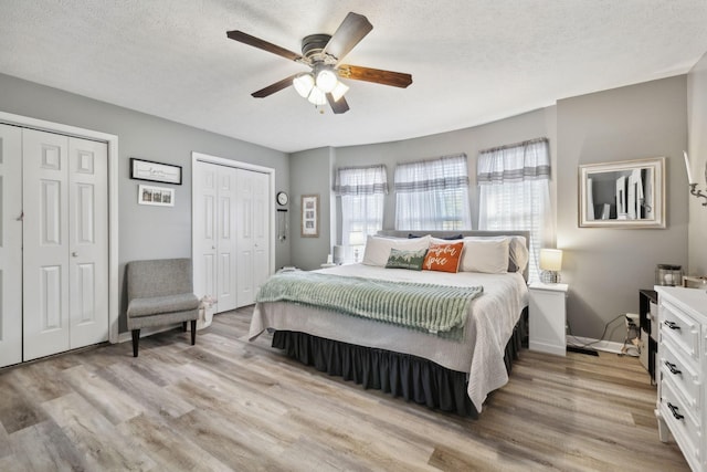 bedroom featuring light wood-style floors, a textured ceiling, and multiple closets