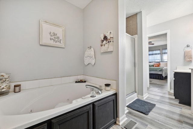 full bath with a stall shower, visible vents, connected bathroom, wood finished floors, and a jetted tub