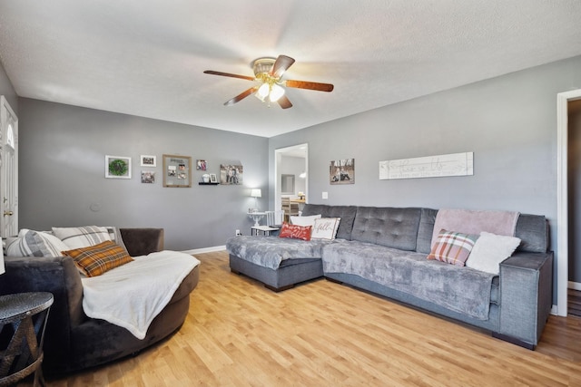 living area featuring ceiling fan, a textured ceiling, baseboards, and wood finished floors