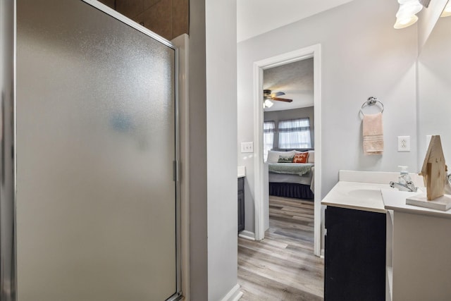 bathroom featuring wood finished floors, a ceiling fan, a shower stall, vanity, and ensuite bath