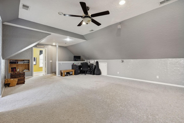 unfurnished office featuring a textured wall, carpet flooring, visible vents, baseboards, and vaulted ceiling