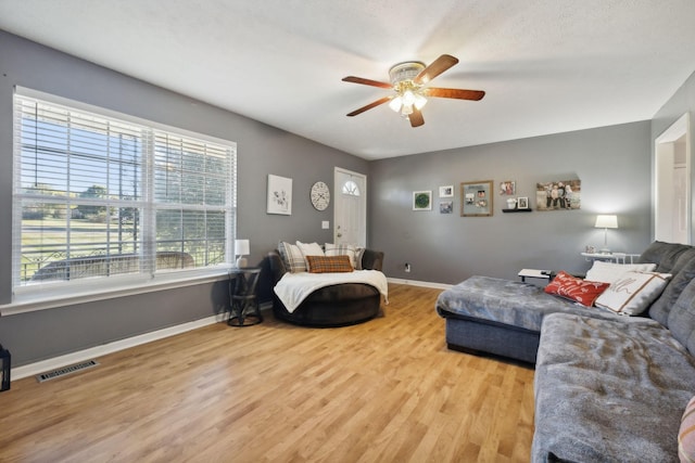 living room with a ceiling fan, wood finished floors, visible vents, and baseboards