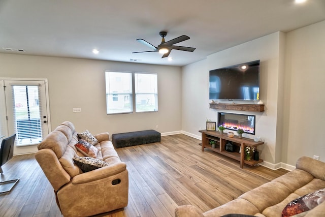 living room featuring a wealth of natural light, a glass covered fireplace, visible vents, and wood finished floors