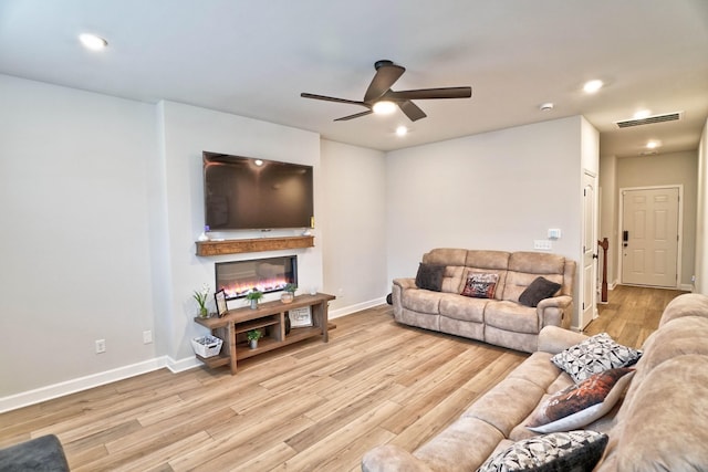 living area with baseboards, visible vents, a glass covered fireplace, wood finished floors, and recessed lighting