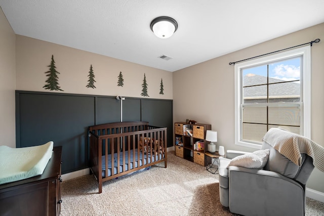 bedroom featuring light carpet, a nursery area, baseboards, and visible vents