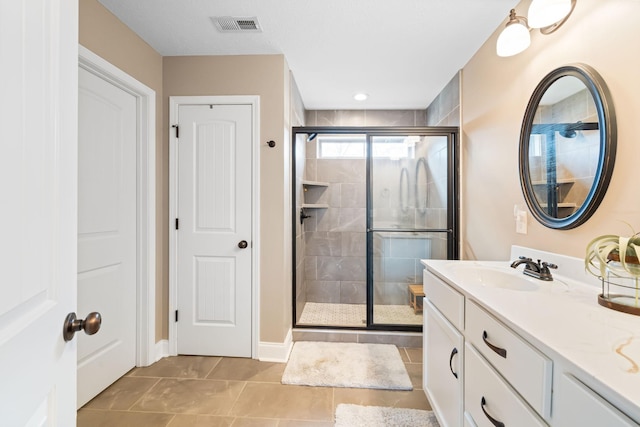 full bathroom with a stall shower, tile patterned floors, visible vents, and vanity