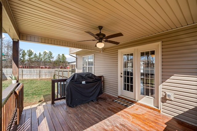 wooden deck featuring a ceiling fan, fence, grilling area, and a lawn