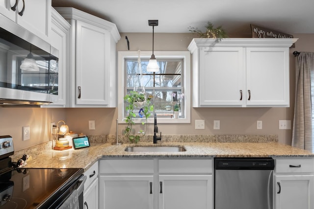 kitchen with white cabinetry, appliances with stainless steel finishes, a sink, and decorative light fixtures