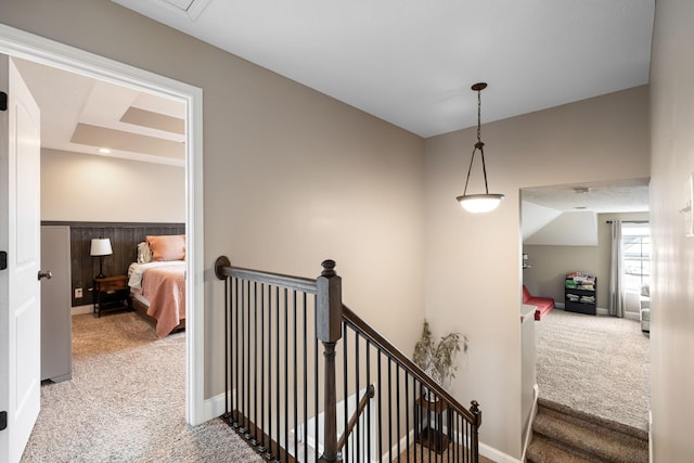 corridor featuring carpet floors, baseboards, and an upstairs landing