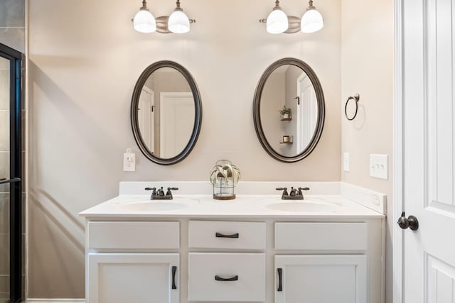 bathroom with an enclosed shower, a sink, and double vanity