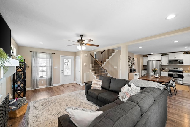 living room featuring light wood finished floors, stairs, a fireplace, and baseboards