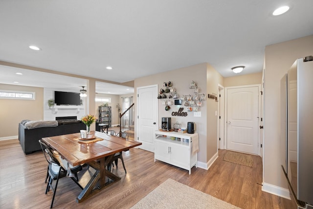 dining area with plenty of natural light, stairway, a fireplace, and light wood-style flooring